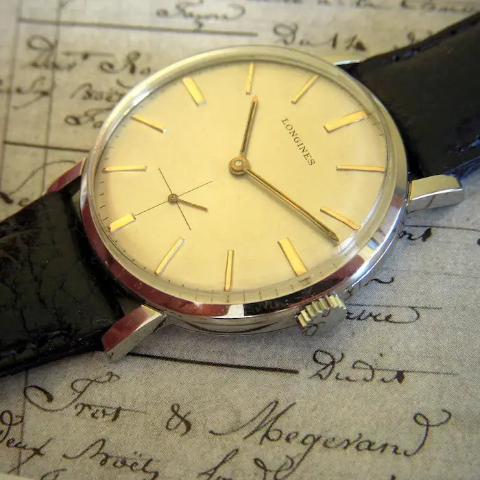 Primer plano de una esfera de reloj vintage con pátina cálida.