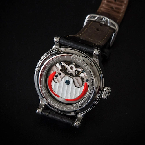 Primer plano de un rotor (masa oscilante) girando sobre el calibre de un reloj automático.